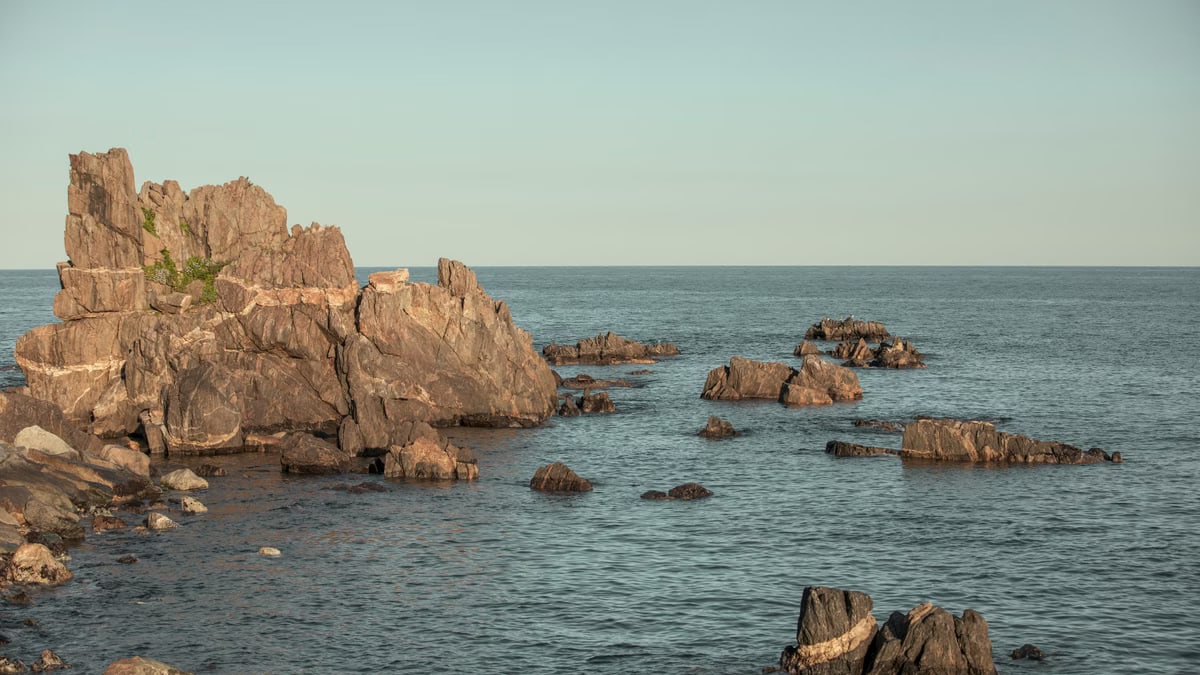 Serene view of rock formations emerging from the sea in Goseong-gun, South Korea, during the day.